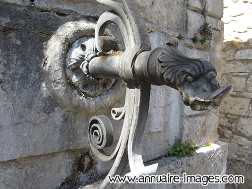 Bec de fontaine en métal soutenu par une ferronnerie